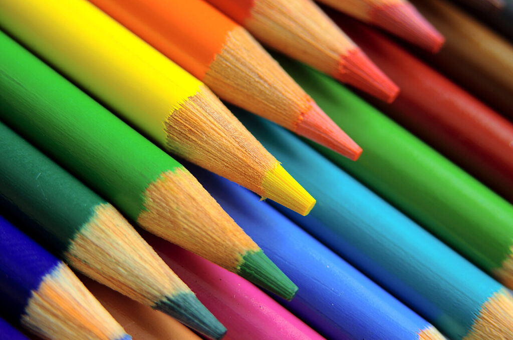 Na obrázku je detail pasteliek rôznych sýtych farieb. Pastelky sú ostré, položené na sebe a smerujú diagonálne z ľavého horného do pravého dolného rohu.